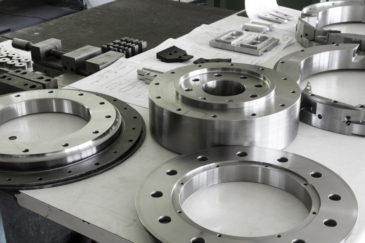 Various metal parts on a table in a factory, including hydraulic cylinders.